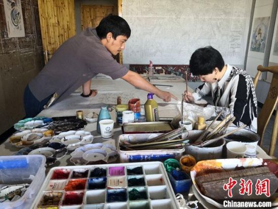 圖為2020年8月下旬，敦煌“80后”畫家張杰龍(左)在為云南麗江“學(xué)生”莫北講解敦煌壁畫的繪畫技巧?！●T志軍 攝