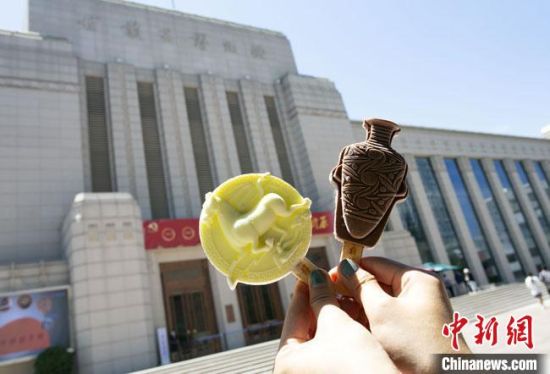 2021年7月30日，游客手拿“銅奔馬”“彩陶瓶”造型的雪糕，在甘肅省博物館前拍照打卡?！「哒?攝