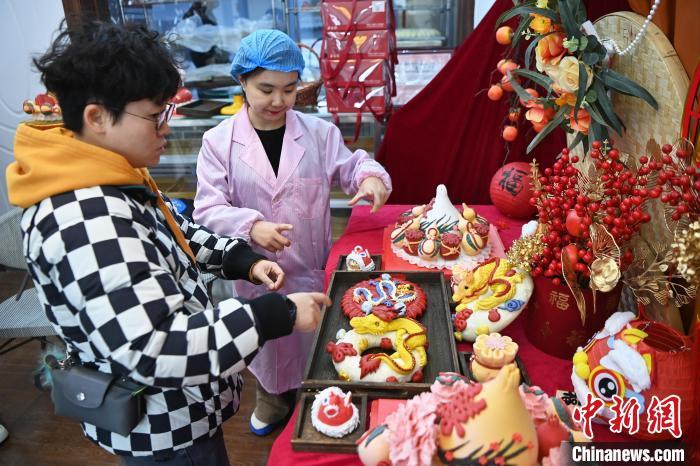1月25日，隨著春節(jié)臨近，蘭州一花饃店“龍”元素花饃熱銷。圖為工作人員向顧客推薦“龍”元素花饃。九美旦增 攝</p><p>