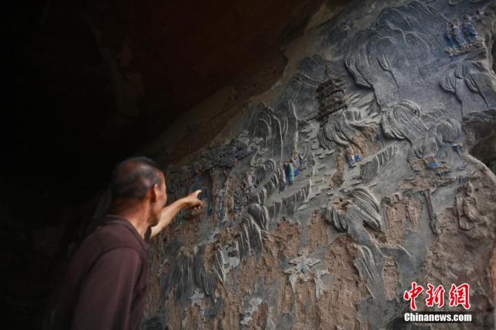 7月15日，甘肅省平?jīng)鍪袥艽h百里石窟長廊羅漢洞石窟內(nèi)，該窟文保員郭建平介紹窟內(nèi)石刻彩繪壁畫。郭建平家中三代人曾自發(fā)保護羅漢洞石窟。羅漢洞石窟遺存40余個窟龕，以北魏至清代風(fēng)格為主。中新社記者 李亞龍 攝