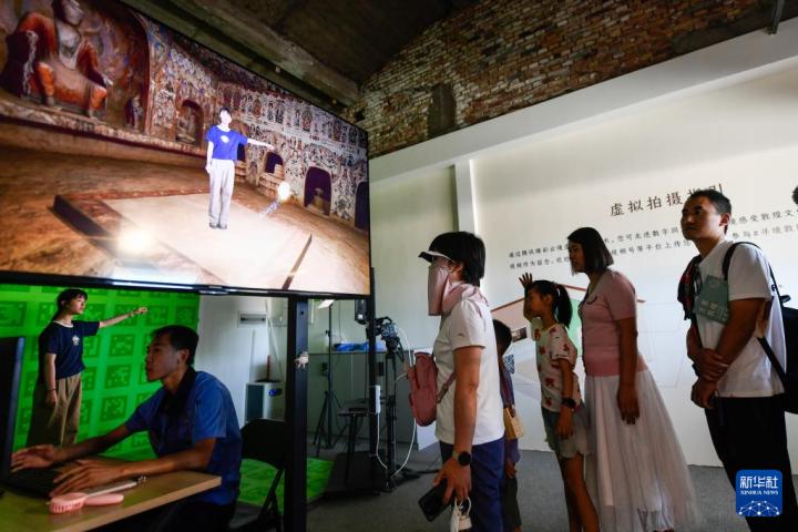 7月22日，游客體驗(yàn)“尋境敦煌——數(shù)字敦煌沉浸展”后，在虛擬演播廳拍攝一段真人與洞窟虛擬場景交互的視頻。新華社記者 郎兵兵 攝</p>
<p>