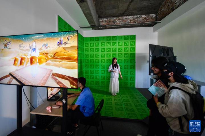 7月22日，游客體驗(yàn)“尋境敦煌——數(shù)字敦煌沉浸展”后，在虛擬演播廳拍攝一段真人與洞窟虛擬場景交互的視頻。新華社記者 郎兵兵 攝</p>
<p>